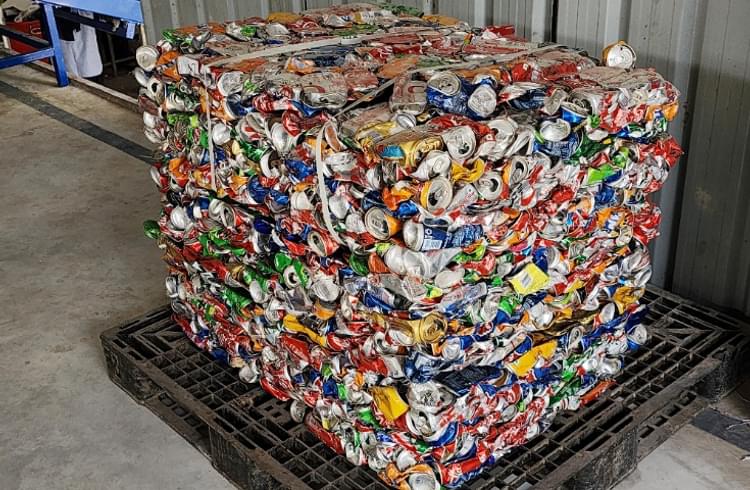 Tin cans are compressed using a bailing machine and salvaged to be recycled by registered recyclers.